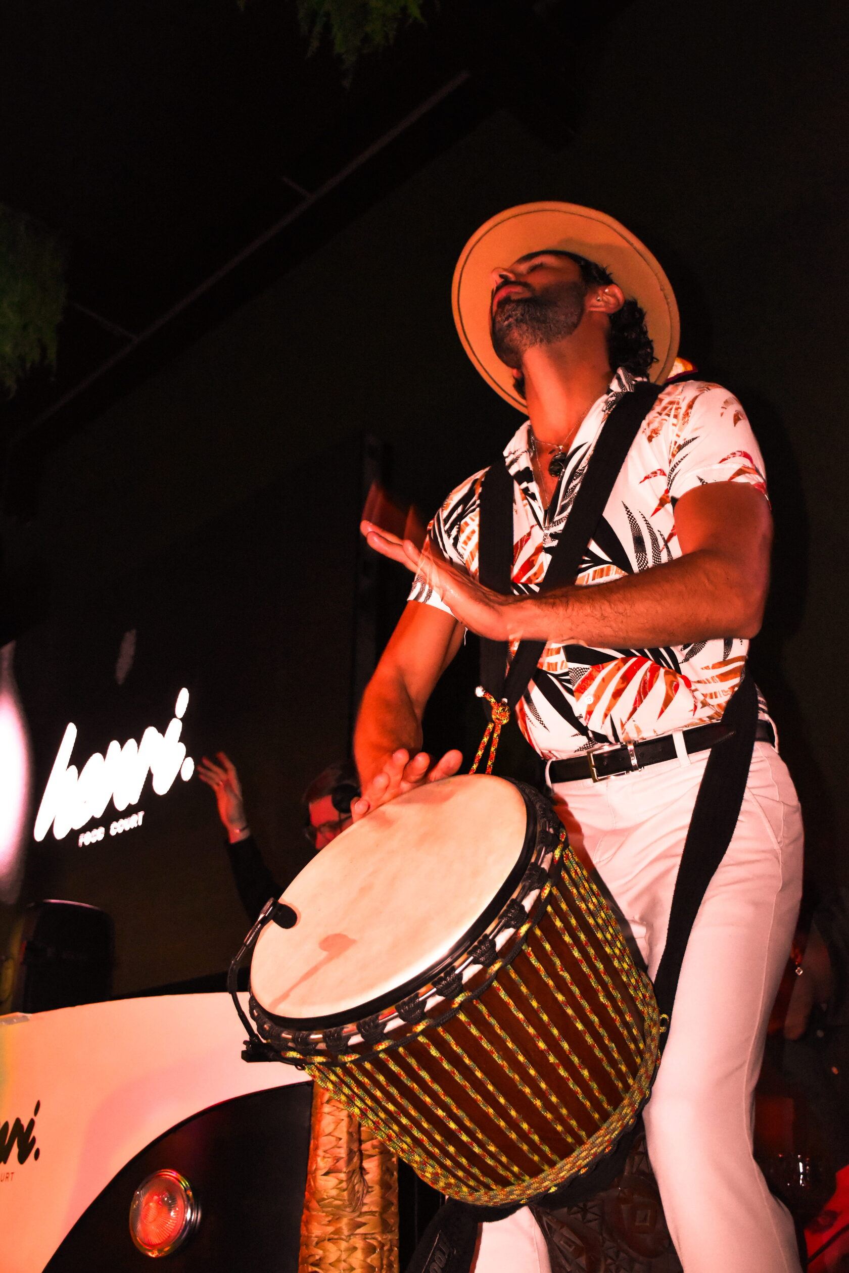 Percussionniste au chapeau de paille jouant du djembé, tête renversée