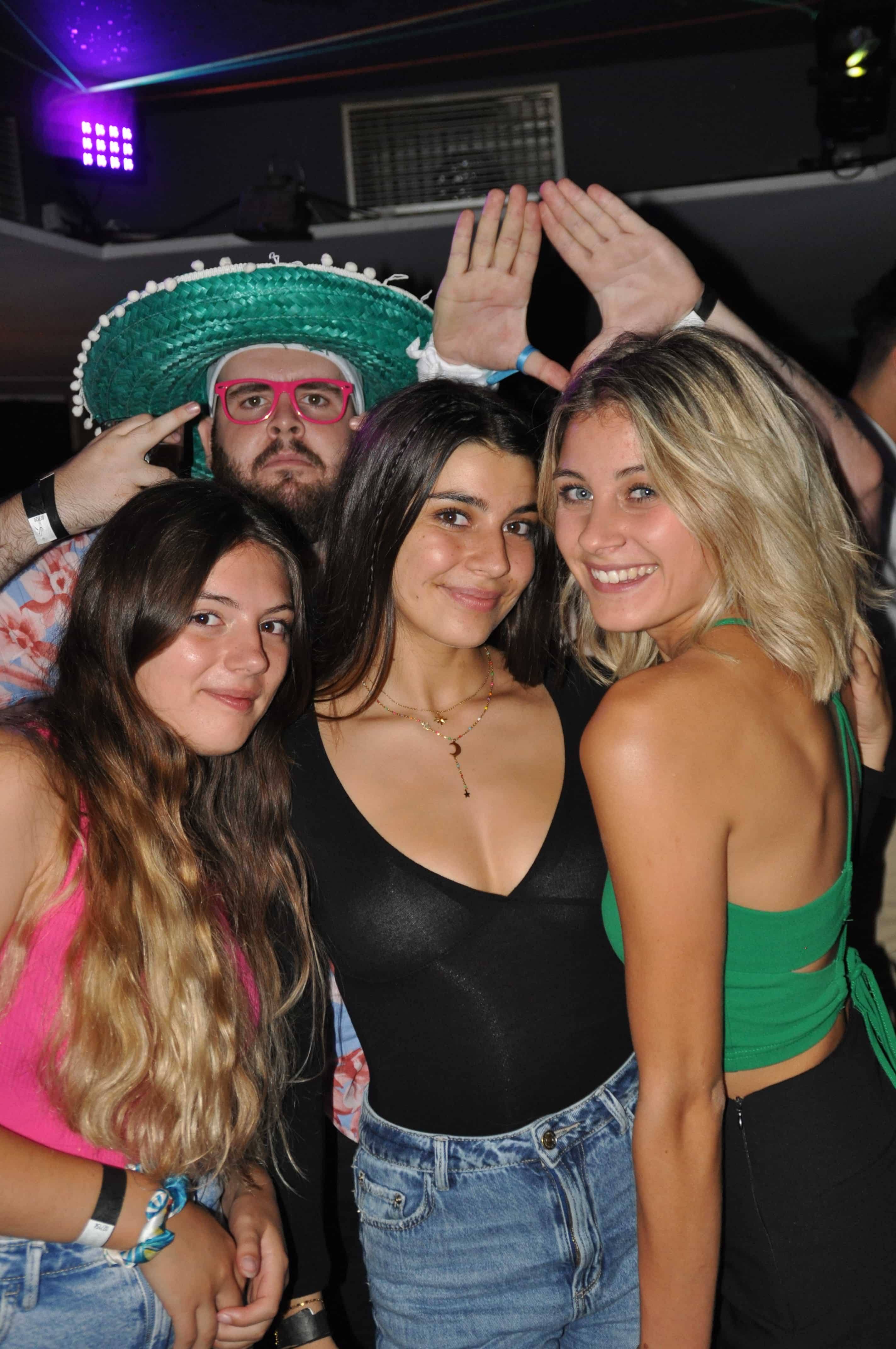 Trois étudiantes et un ami en sombrero posant, mains levées