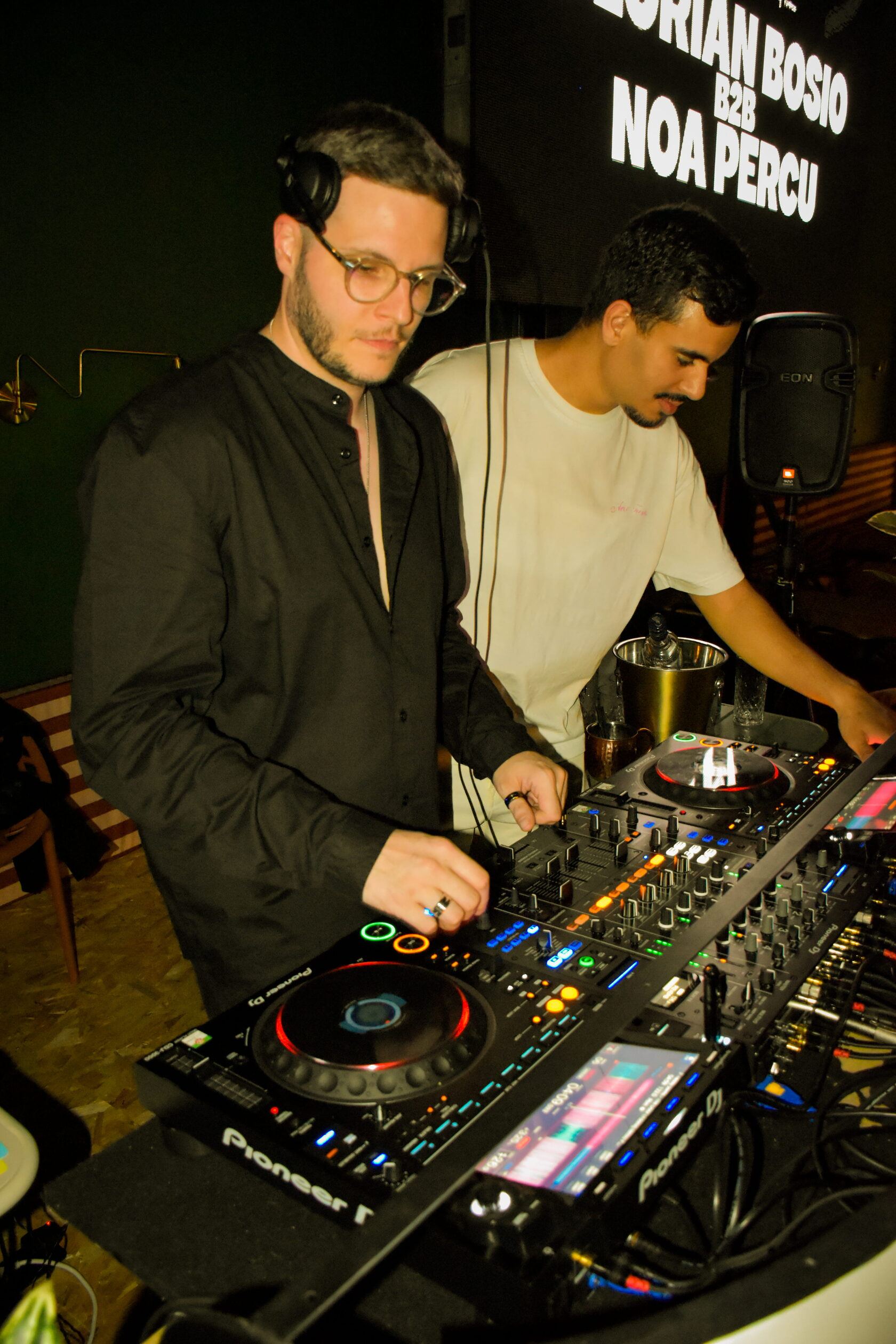 Deux DJ aux platines, le nom des artistes projeté derrière eux