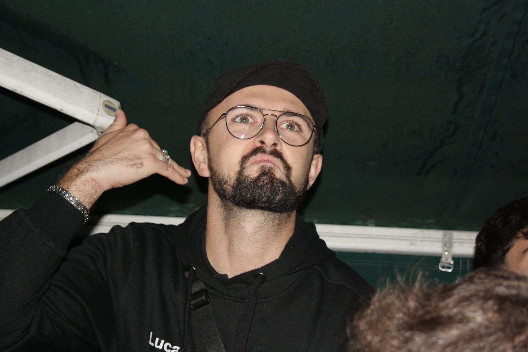 Étudiant barbu à lunettes posant sous une bâche