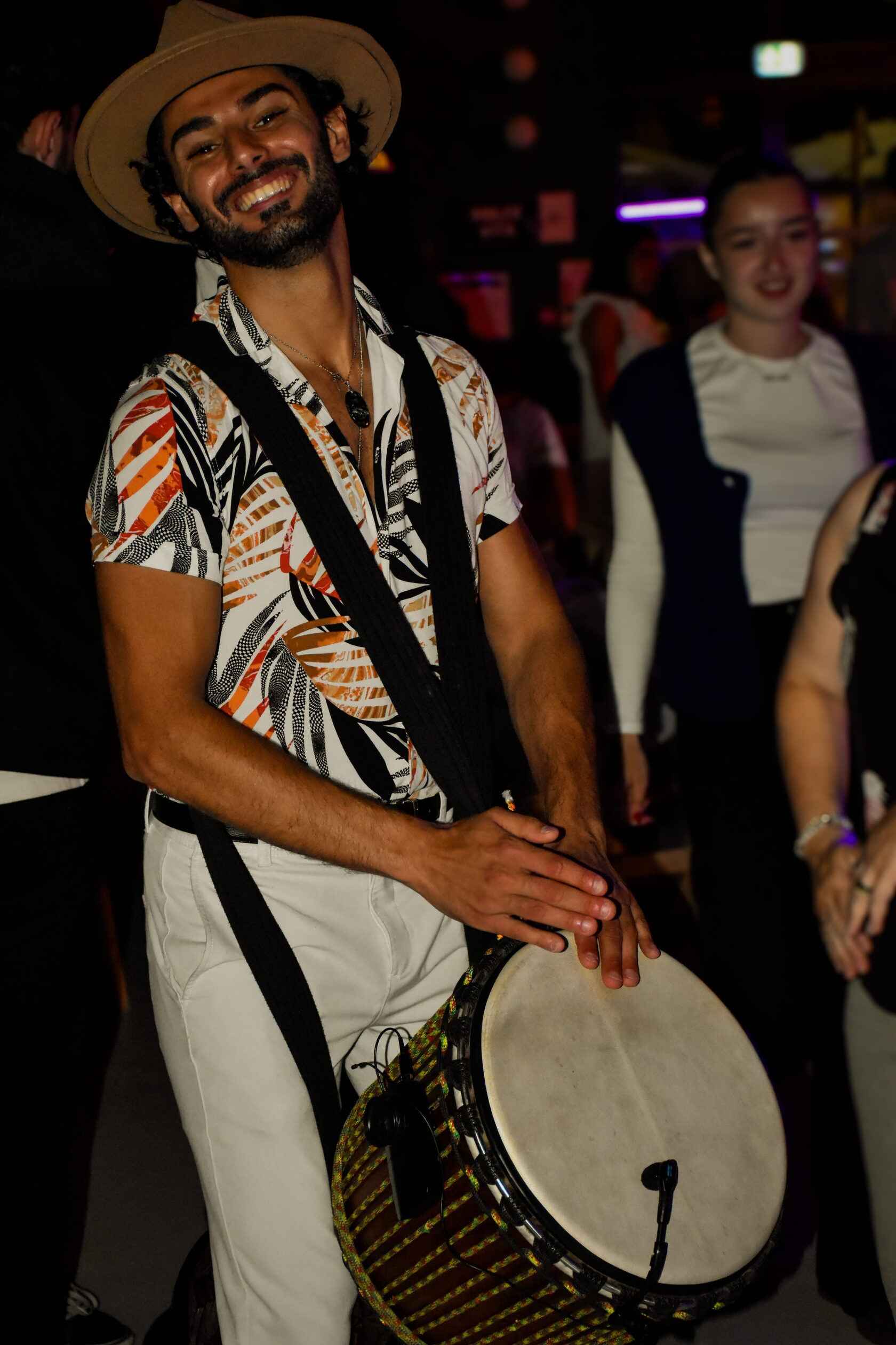 Percussionniste souriant au milieu du public, djembé en bandoulière