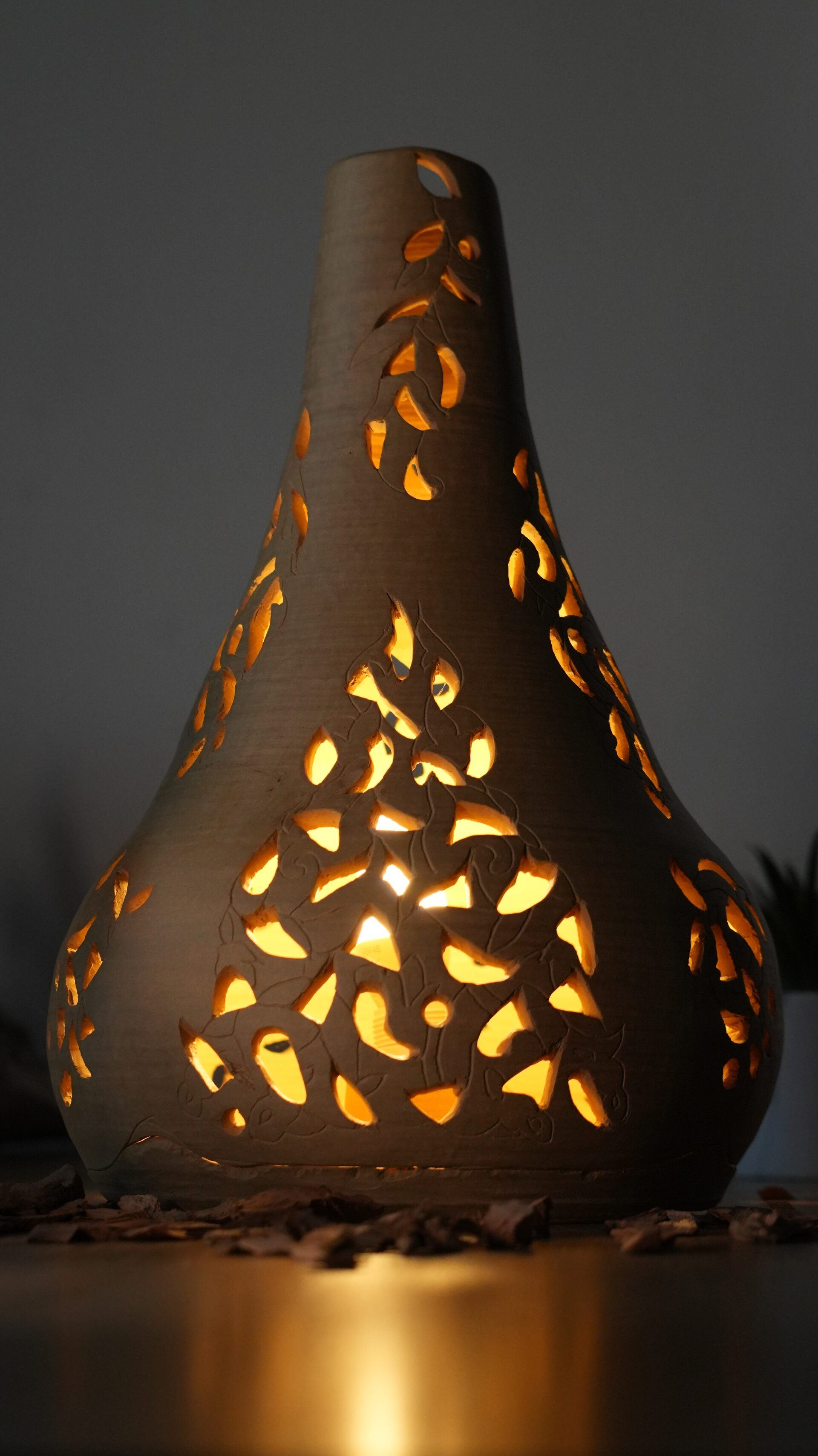 Lampe en céramique ajourée projetant des motifs de lumière